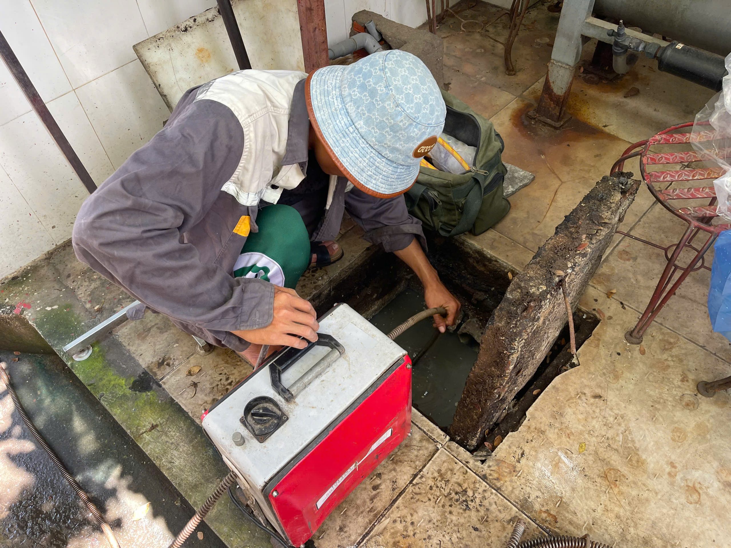 Thợ xử lý thông tắc đường cống bằng máy lò xo chuyên dụng.